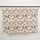 Full yard of Tonic Living Paloma Fabric in Mauve hanging to show the scale and drape of its muted purple floral pattern.