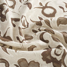 Close up of Tonic Living Paloma Walnut drapery fabric showing stylized coffee brown flowers and scrolling leaves with a watercolour effect.