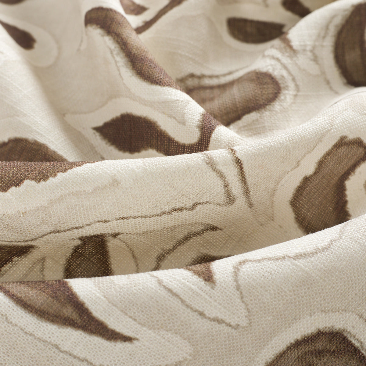 Close up of Tonic Living Paloma Walnut curtain fabric showing stylized coffee brown flowers and scrolling leaves with a watercolour effect.
