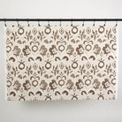 Full yard of Tonic Living Paloma Fabric in Walnut hanging to show the scale and drape of its coffee brown floral pattern.