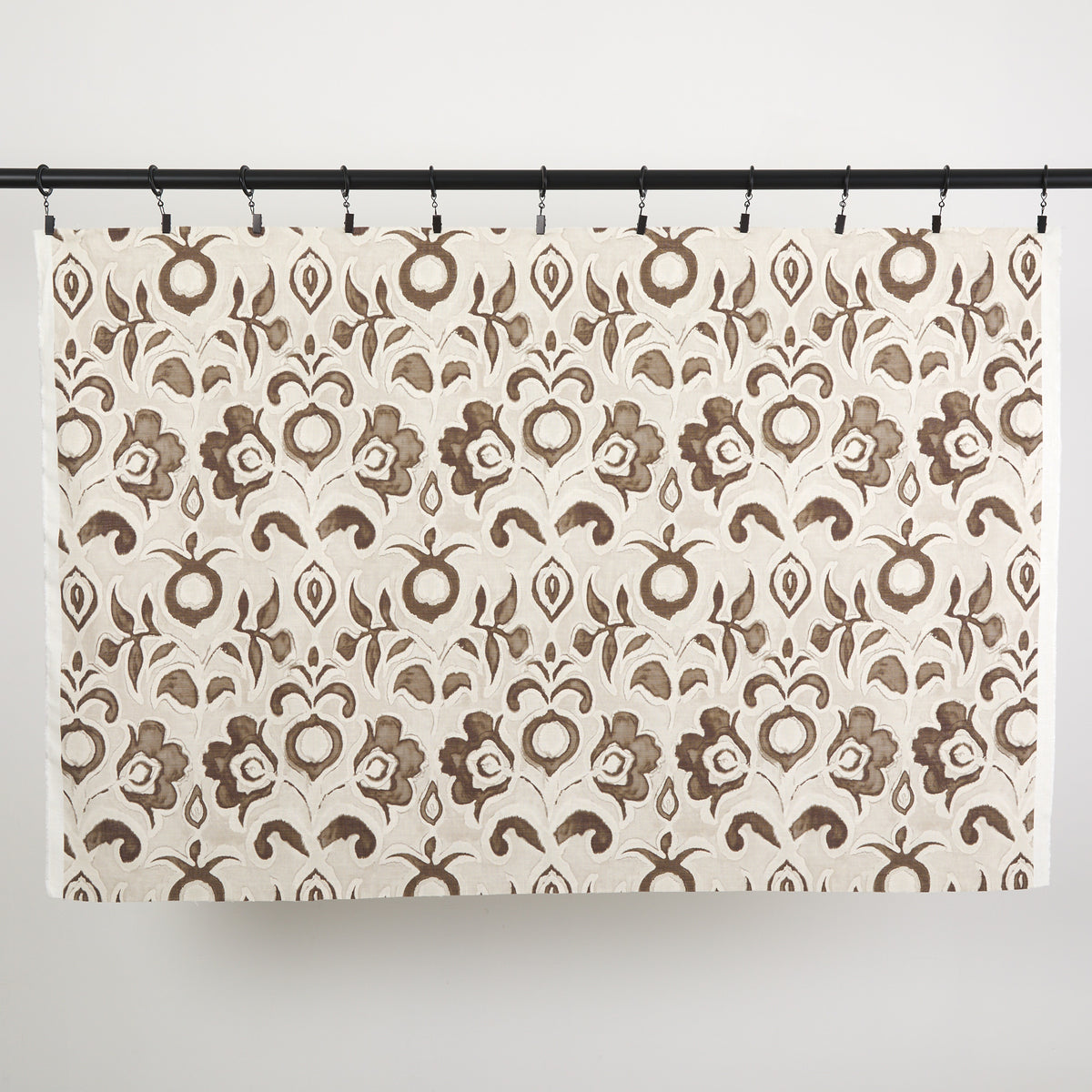 Full yard of Tonic Living Paloma Fabric in Walnut hanging to show the scale and drape of its coffee brown floral pattern.