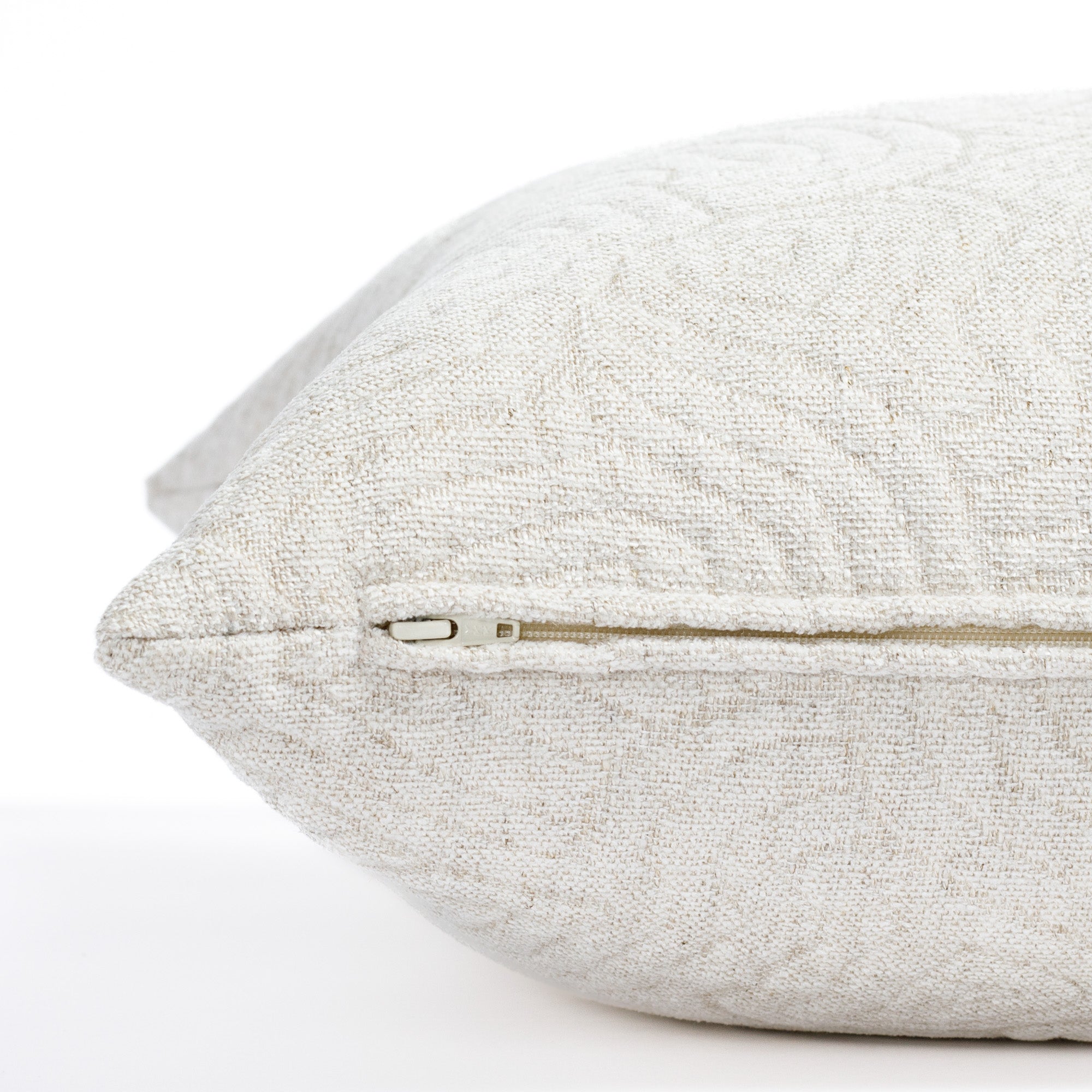 a quilted white abstract patterned pillow : close up zipper view