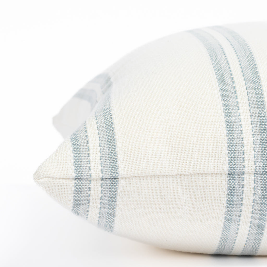 a white and chambray blue striped outdoor throw pillow : close up side view