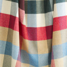 Close up of Tonic Living Rowan Check Orchard wool blanket showing its sky blue, cherry red, spruce green, camel, and beige check with subtle herringbone texture.