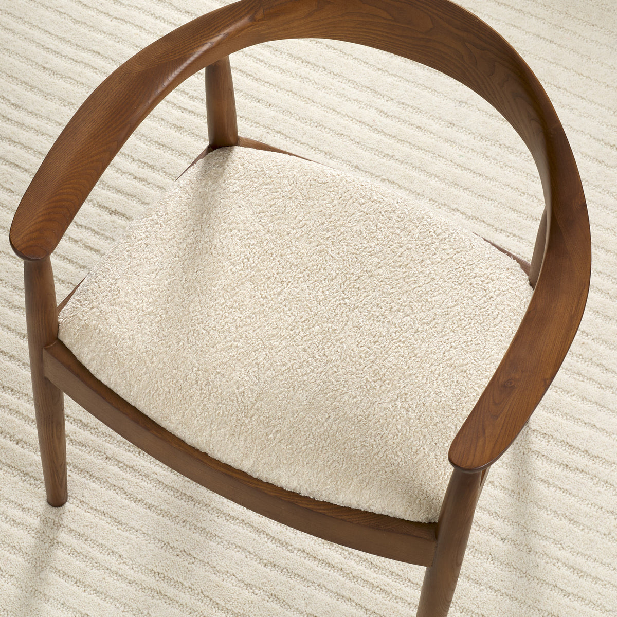 Tonic Living Rupert Parchment cream bouclé upholstery fabric shown on a dining chair seat.