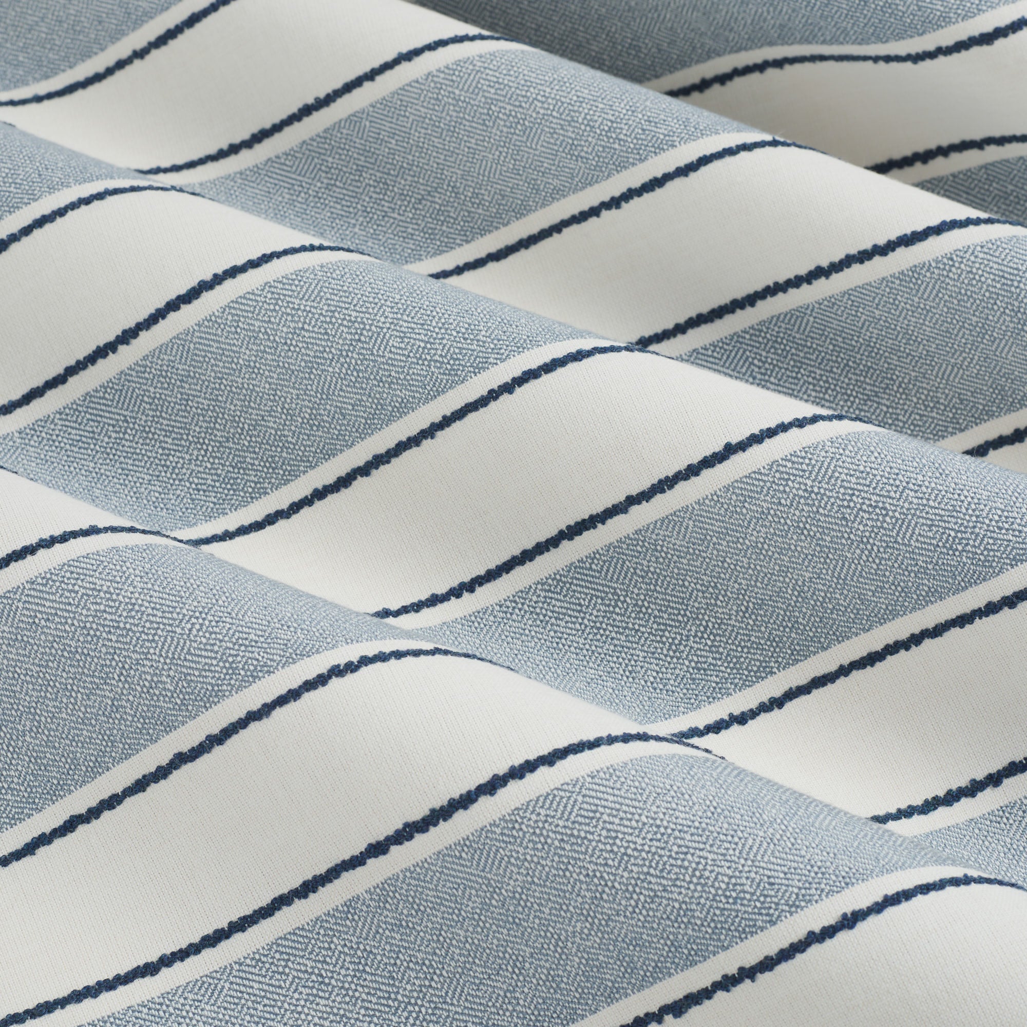 Tonic Living Sentiment Sunbrella Denim performance fabric showing movement in a bold blue striped design.
