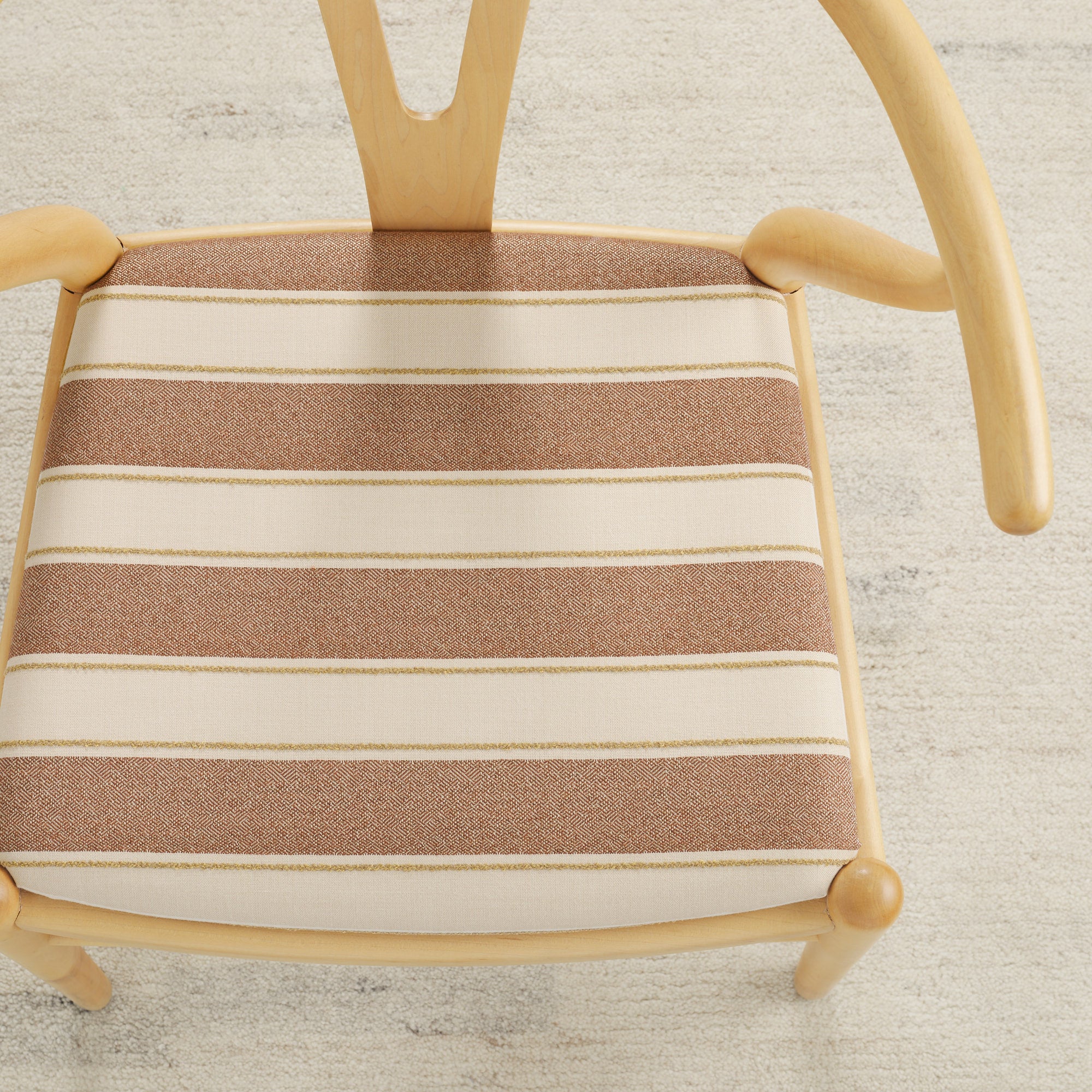 Tonic Living Sentiment Sunbrella Terracotta indoor/outdoor upholstery fabric on a dining chair seat in terracotta and sand stripe.