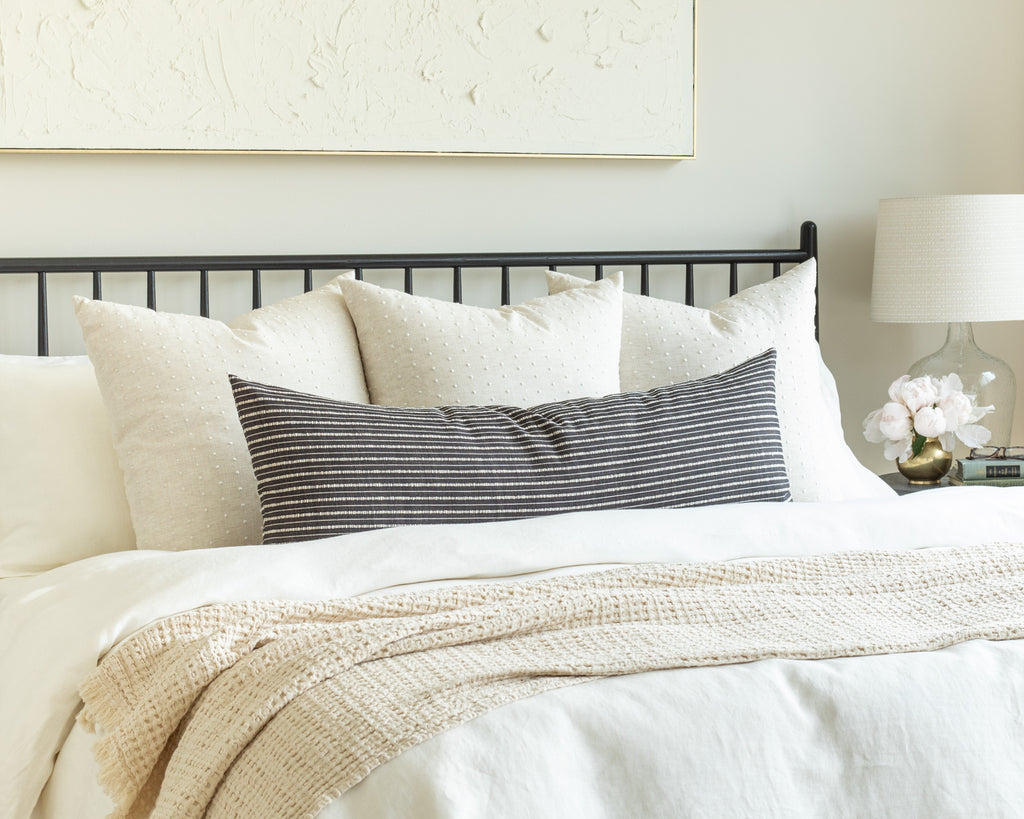 black and cream bed pillow pairing: cream throw pillows with a high contrast charcoal and cream stripe bolster bed