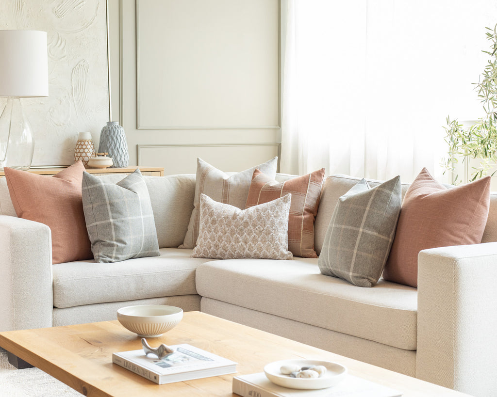 Earthy terracotta and grey sectional pillow pairing: a combination of warm, earthy solids with a classic, oversized plaid, farmhouse stripe and small-scale organic pattern