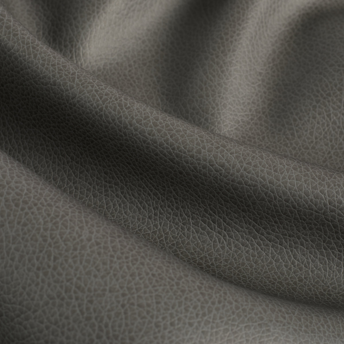 Close up of Tonic Living Smythe Charcoal faux leather upholstery fabric showing its deep charcoal colour and realistic leather grain.