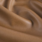 Close up of Tonic Living Smythe Saddle faux leather upholstery fabric showing its rich saddle brown colour and realistic leather grain.