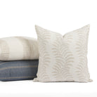Tonic Living Swoon Sand outdoor cushion styled in front of cream and blue throw pillows.