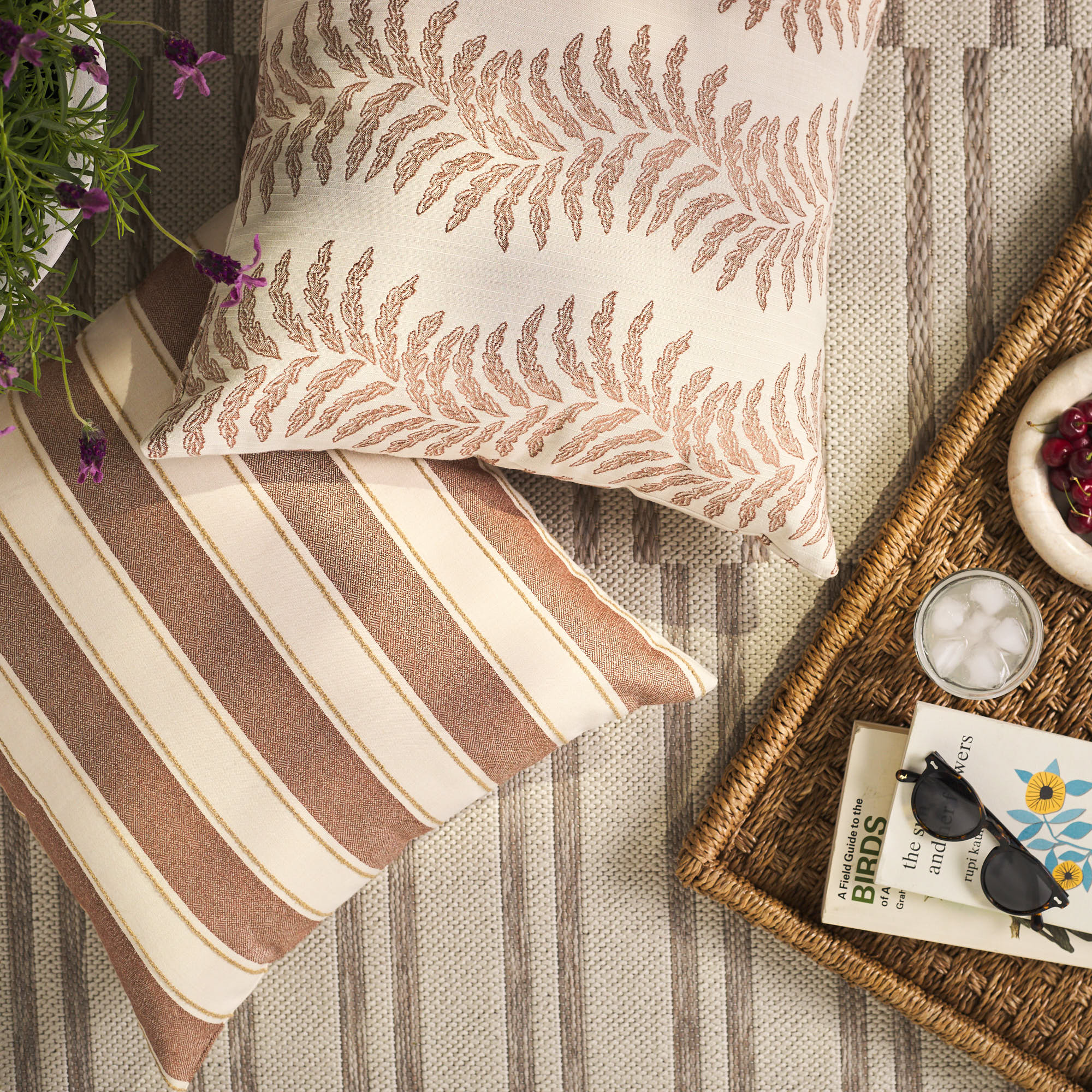 Overhead view of Tonic Living Sentiment Terracotta decorative cushion with Swoon Terracotta pillow on an outdoor rug.