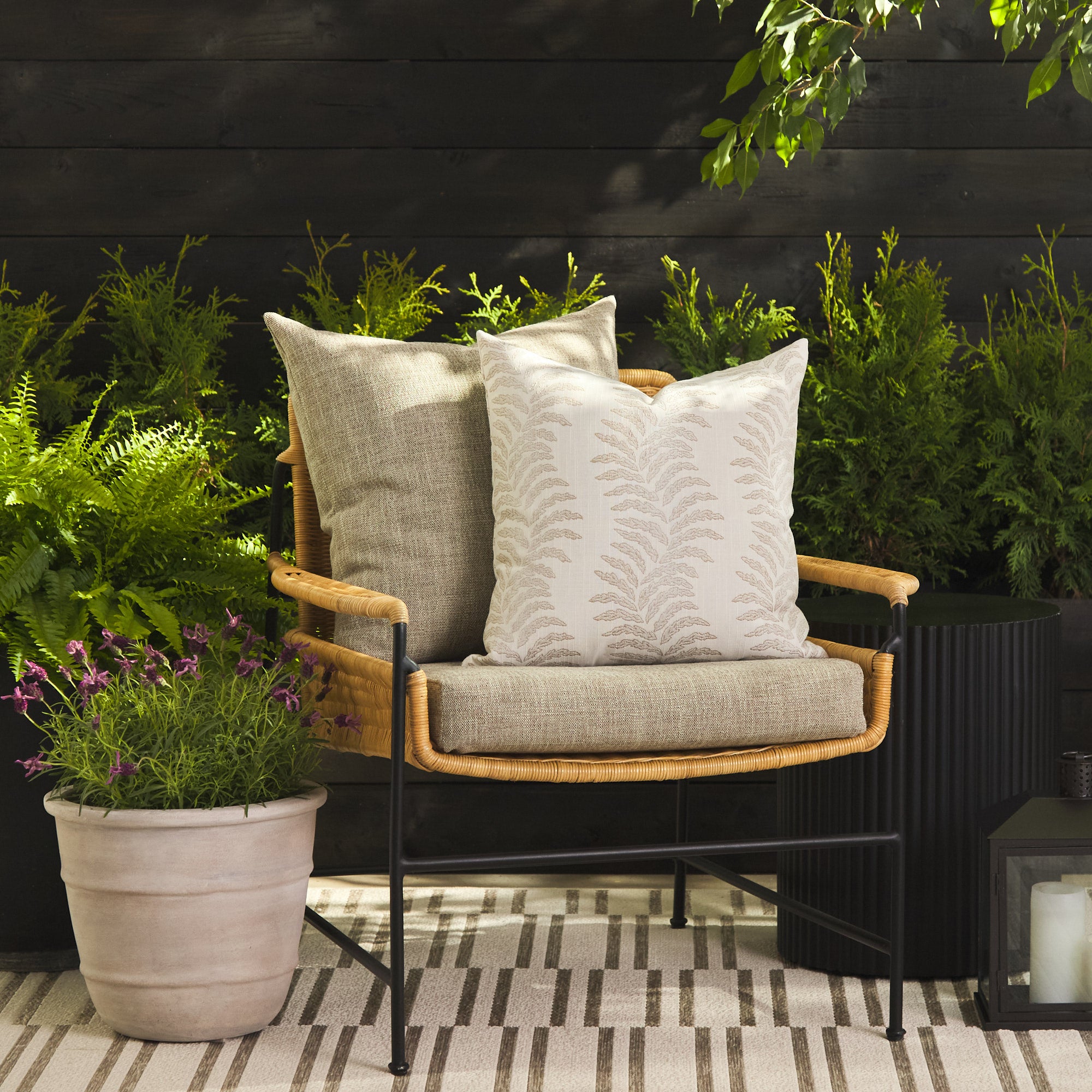 Tonic Living Swoon Sand throw pillow styled on a chair with the Troy Tweed 22x22 cushion outdoors.