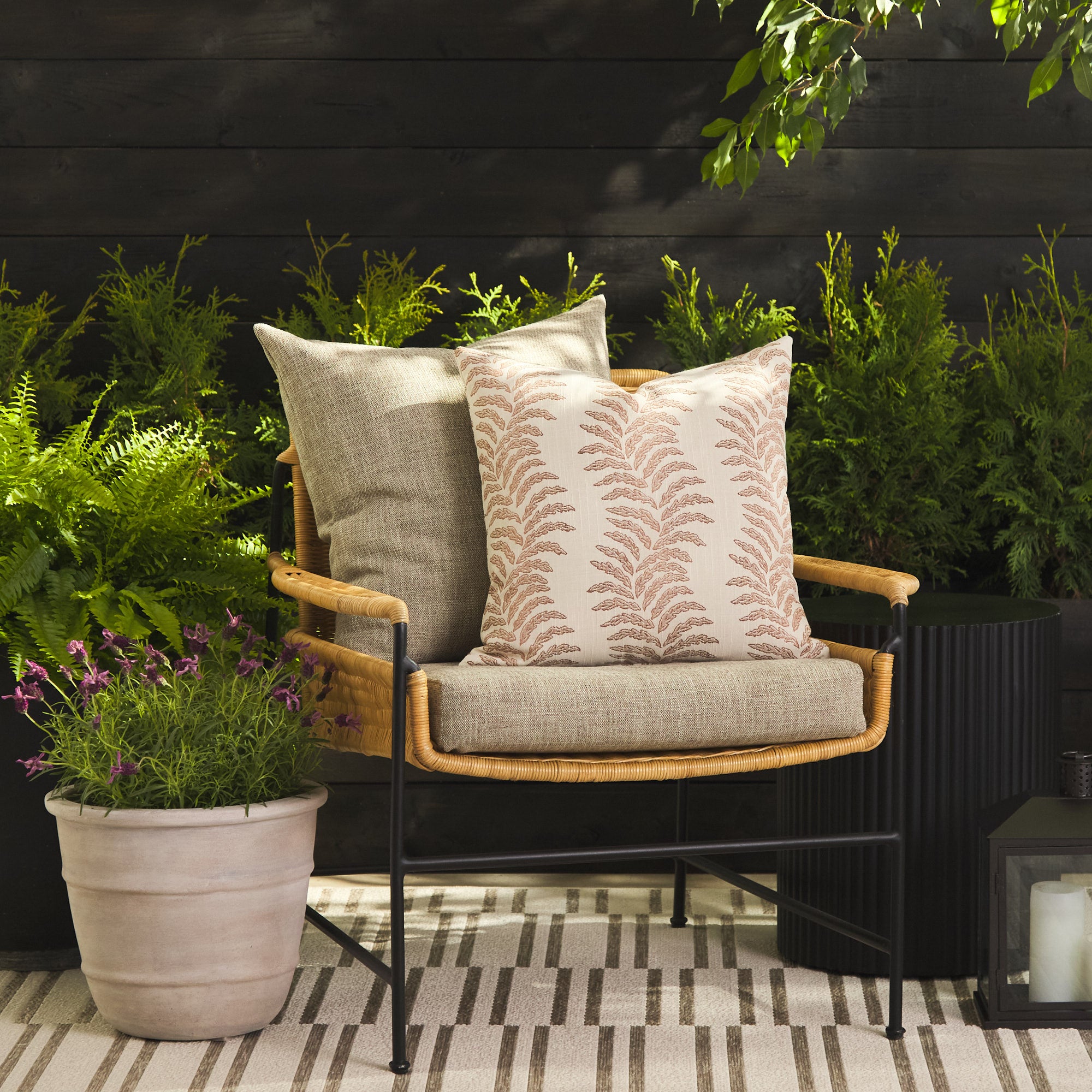 Tonic Living Swoon Terracotta outdoor cushion styled on a chair with the Troy Tweed 22x22 pillow in an outdoor setting.