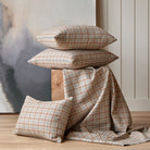 Tonic Living Vesper Plaid paprika pillows stacked on a pedestal with matching fabric draped in the scene.