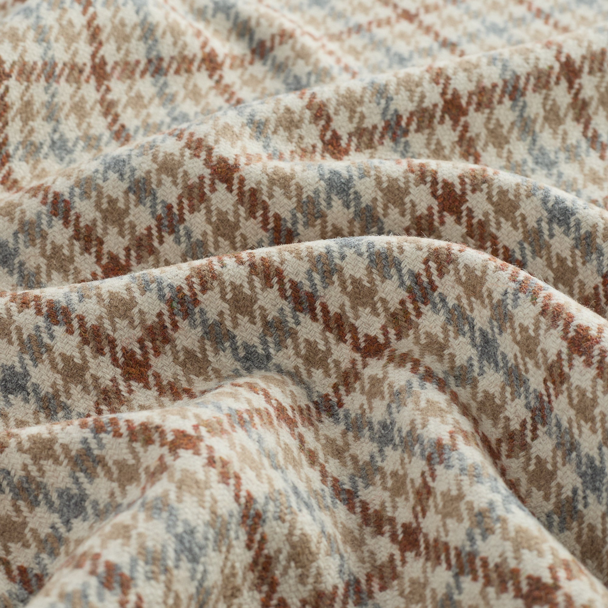 Close up of Vesper Paprika houndstooth upholstery fabric showing its beige, blue, and rust pattern.