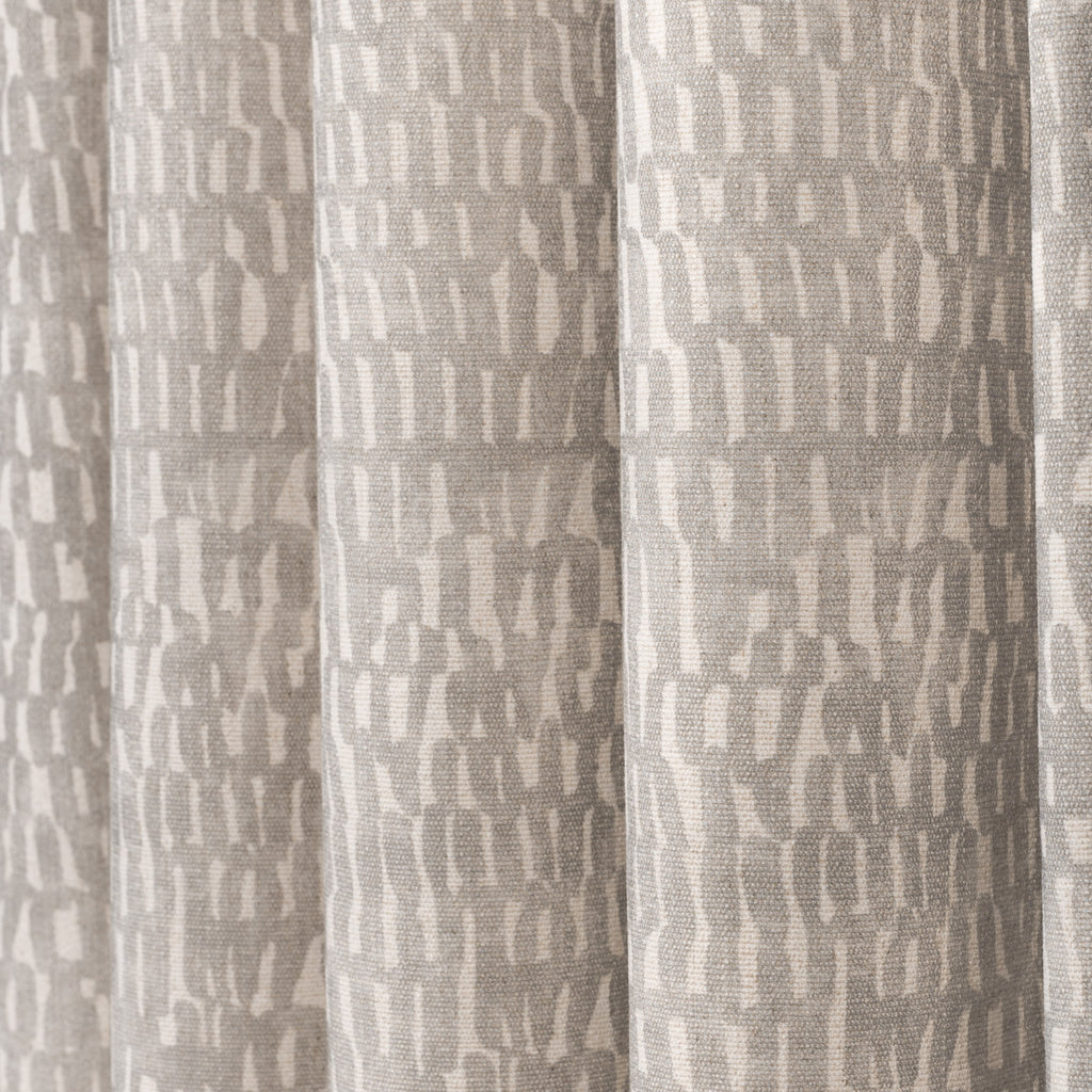Avareno Silver, a light grey and sandy beige small scale abstract print fabric : close up draped view