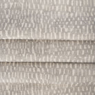 Avareno Silver, a light grey and sandy beige small scale abstract print fabric : close up with soft folds