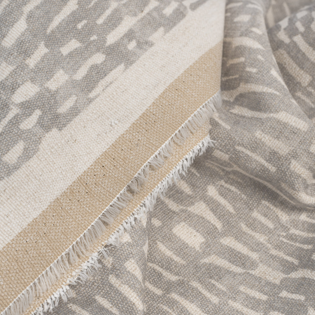 Avareno Silver, a light grey and sandy beige small scale abstract print fabric : close up selvage edge
