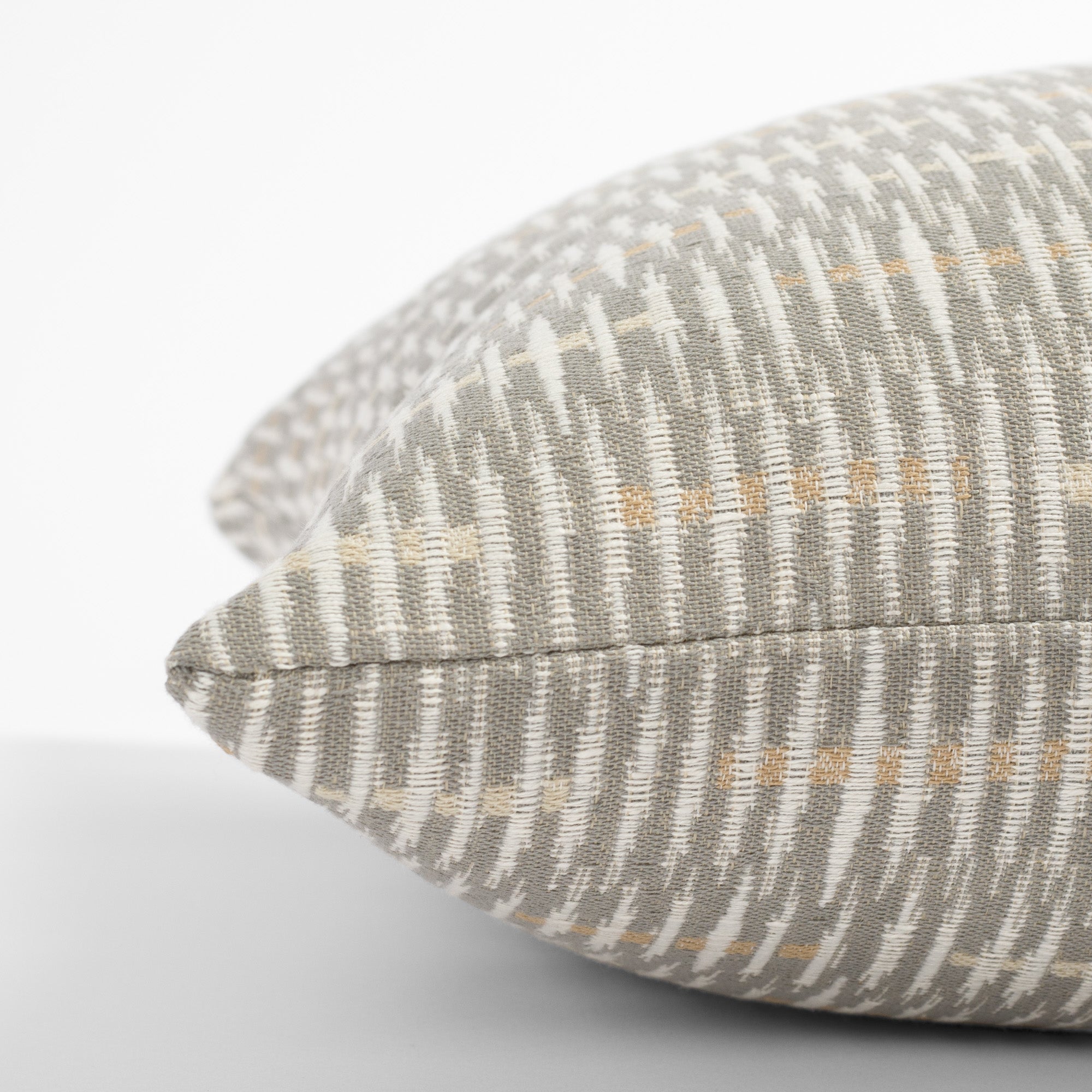 a grey, beige and cream graphic abstract pattern throw pillow : side view