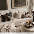 Brown, natural, textured and patterned pillows on a sectional sofa in a neutral living room. Home of Brooke Morales.