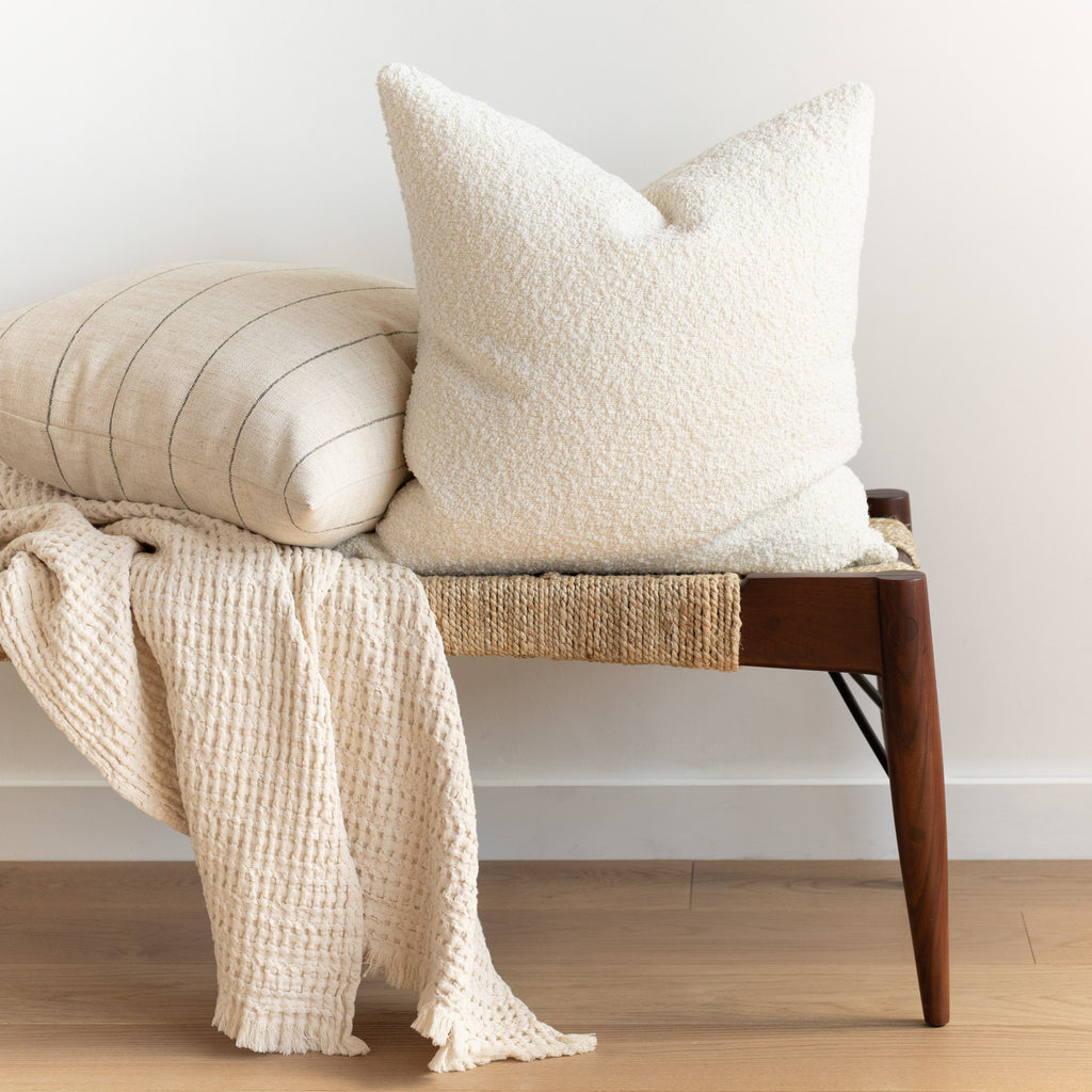 neutral decor: Cambie chalk cream boucle pillow, Dunrobin stripe beige burlap pillows and Lena Natural throw blanket on a bench