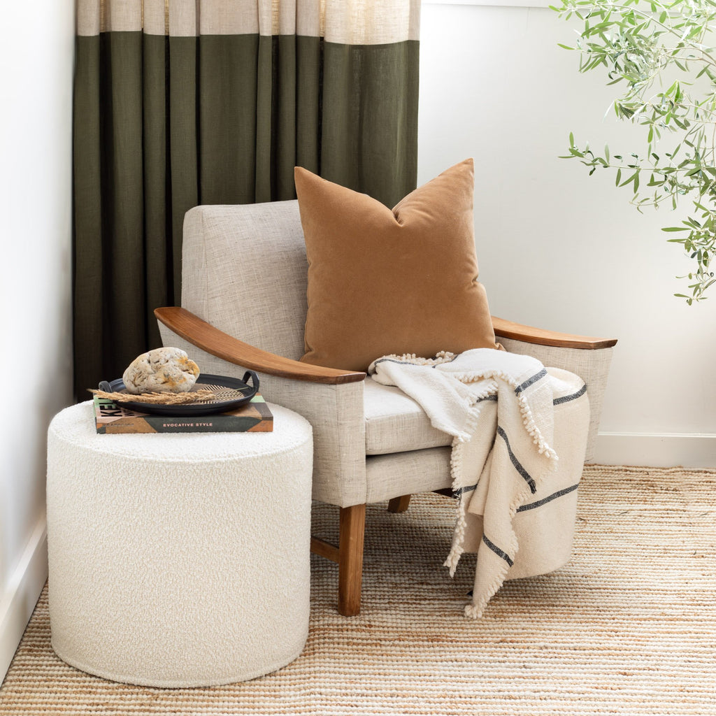Arm chair vignette: Cambie Boucle Round Ottoman Chalk used as a side table, Valentina Nutmeg pillow and Rafael Cream blanket from Tonic Living
