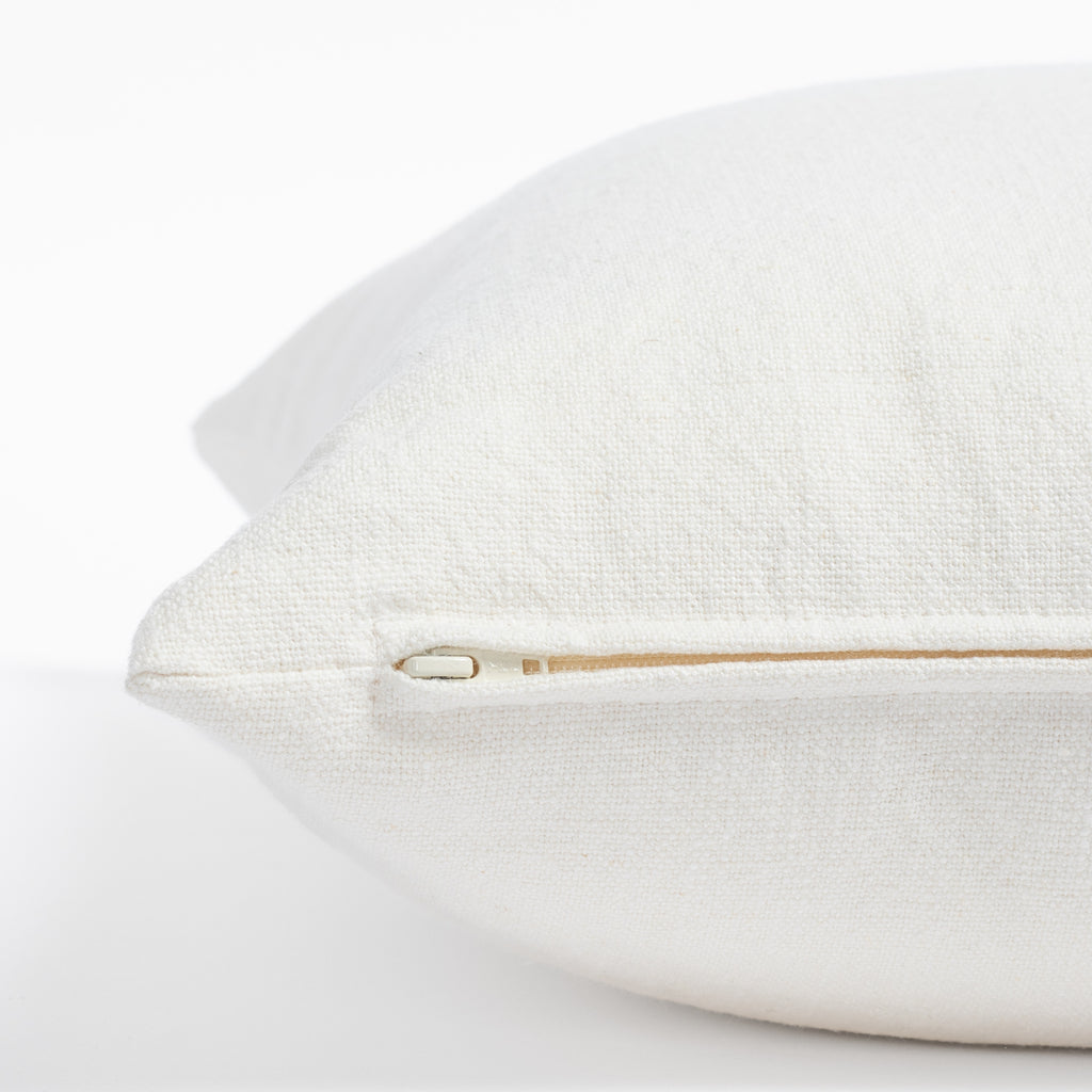 a cream white pillow: zipper detail