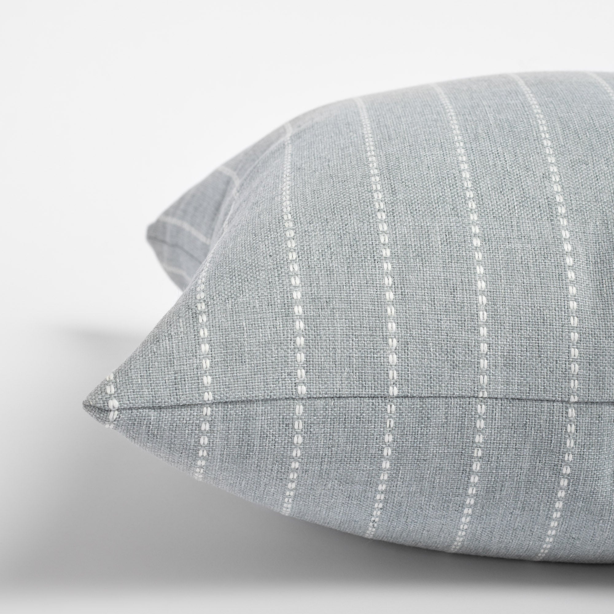 Fontana Cloud 20x20 pillow, a pale blue grey and white vertical stripe indoor outdoor pillow : close up side view