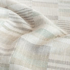 a geometric patchwork patterned upholstery fabric in costal watery green, sand, and grey colours