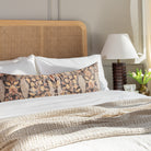 a cozy pillow with a beautiful botanical print in warm earthy colours on a queen bed