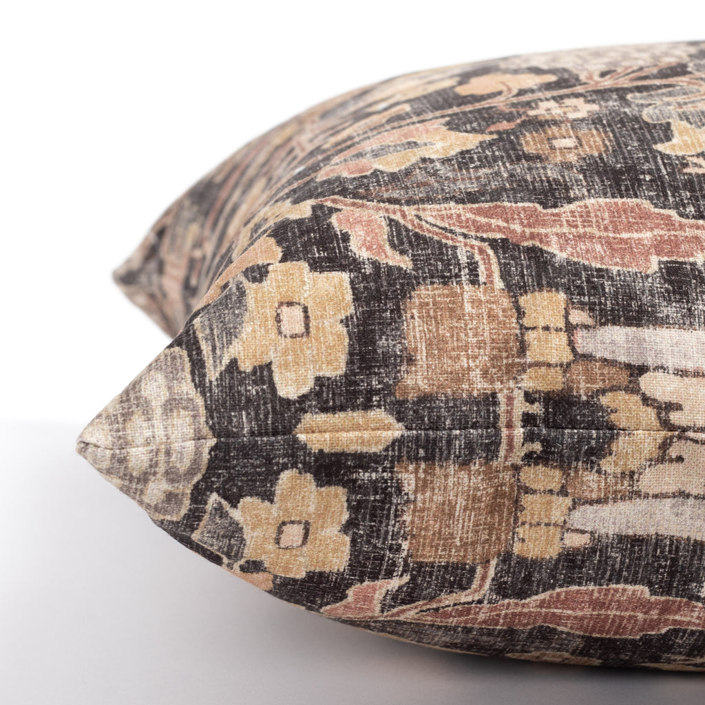 a faded black and earth toned vintage floral tapestry print decorative pillow : close up side view