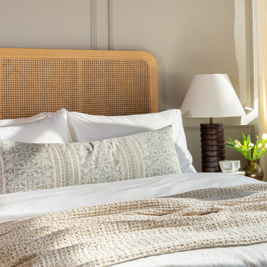 a tan and light blue-grey motif intricate block print bolster pillow on a queen bed