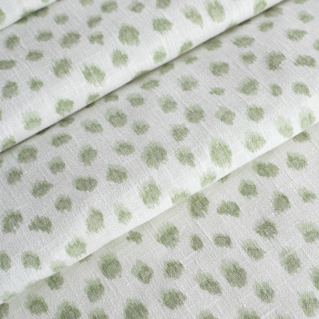 a white and green inky polka dot print fabric