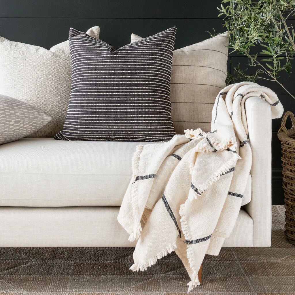 Black and white stripe pillow with cream and beige pillows on a cream sofa