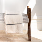 Rafael Cream, a cream with black stripe chunky weave cotton throw blanket displayed on a bench