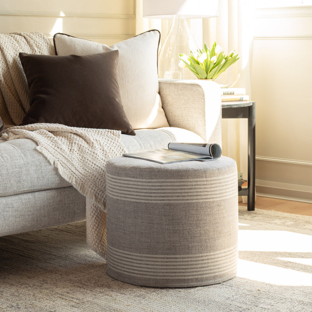 a versatile natural tan and faded black striped linen round ottoman : used as a side table or a space to rest you legs
