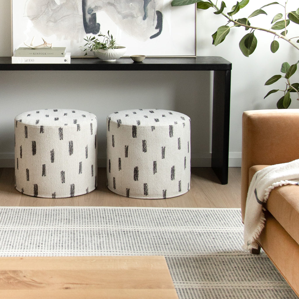 Tonic Living home decor : Stratus cream and black round ottomans tucked under a console 